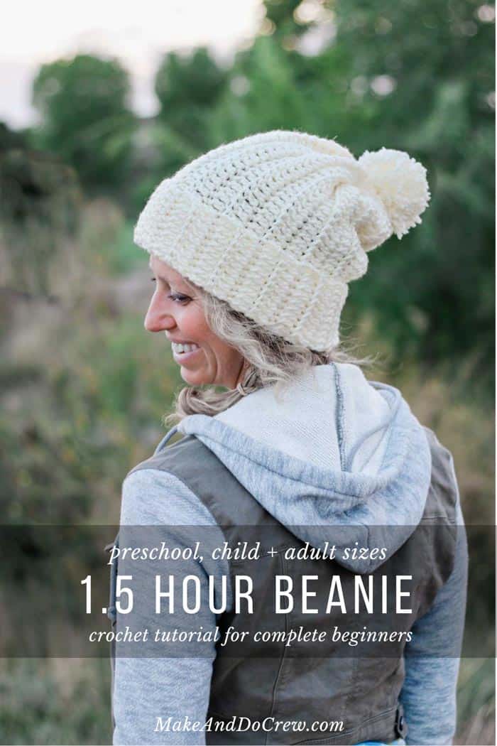 A woman facing backwards while looking down wearing a ribbed crochet beanie with pom poms.