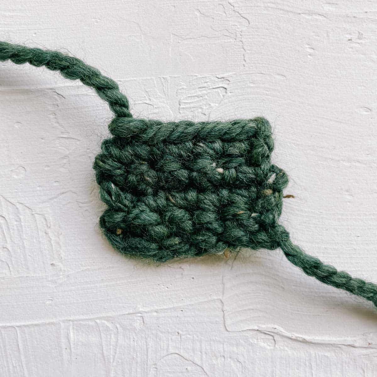 A small crochet rectangle made from green yarn.