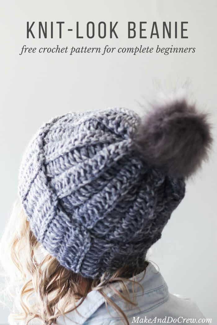 The back view of a woman wearing a gray knit-looking crochet hat with a faux fur pom pom.

