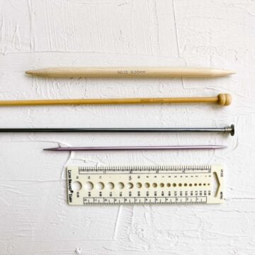 Different types of straight knitting needles made of metal, bamboo and wood.