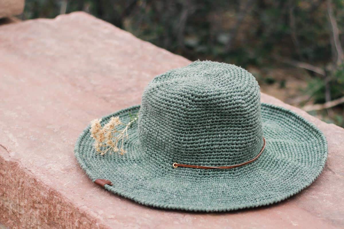 A crochet fedora sun hat made with Lion Brand Rewind Yarn in the color "Olive You" with grommets and a chin strap.