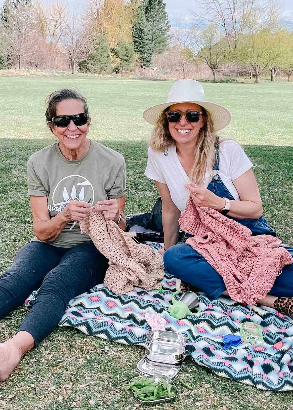 Jess Coppom (daughter) and Jacque Shank (mother) crocheting outside together.